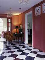 Hallen gir et gedigent første-inntrykk med sjakkmønstert marmorgulv og rødmalte vegger. Både glassdøren inn til stuen og døren til skyvedørsgarderoben er malt røde. Dette roer ned rommet. To prismekroner i taket understreker det elegante inntrykket.