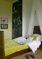 Den fjerde veggen er malt limegrønn, som sengeteppene fra Anoucha Design. Skapdørene har fått tavlemaling og brukes til utfoldelse av kreativ aktivitet.