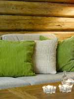 Putene i sofaen tar opp grønnfargen på endeveggen i kjøkkenet og lager på den måten sammenheng  mellom rommene.