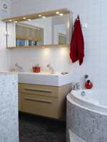 Badet har en kombinasjon av enkle, hvite fliser og turkis marmormosaikk. Det lille rommet rommer mye, med både stort massasjebadekar og dobbel vask.