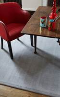 KLART FOR BESØK: Stilig med grått teppe mot rød stol og bord. Teppe er fra Jacaranda/INTAG. 