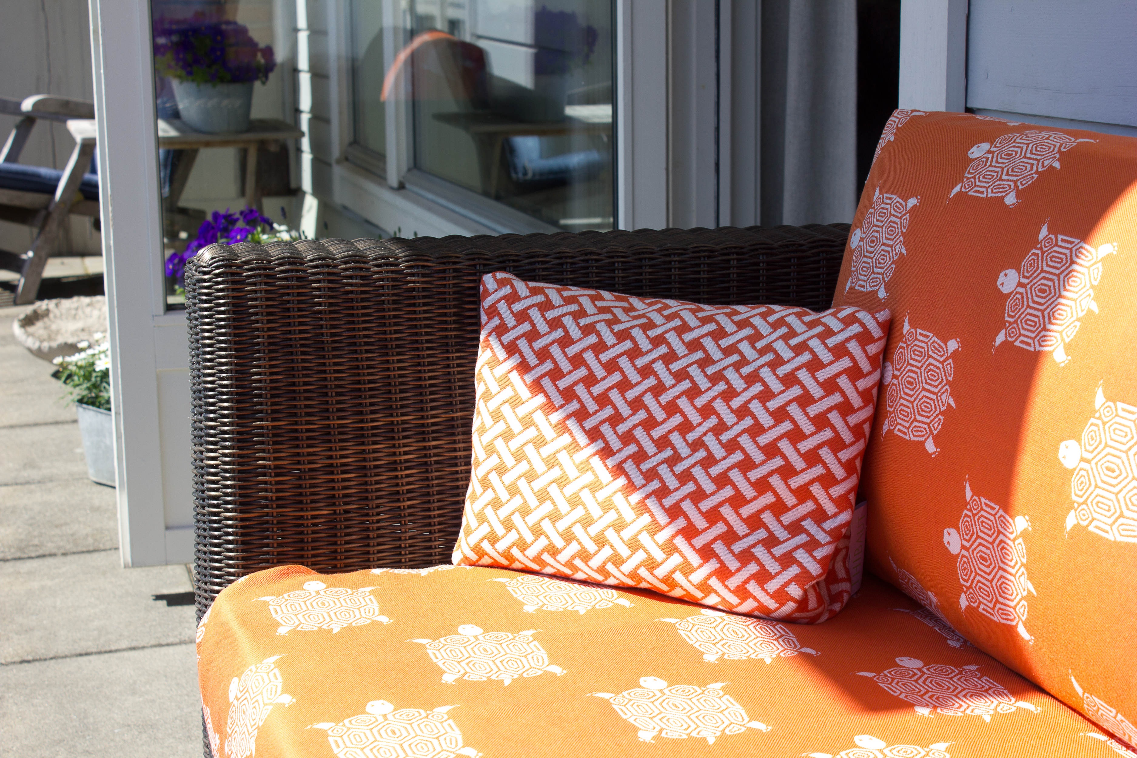 Med noen fargerike tekstiler blir de mørke rottingmøblene straks mer sommerlige.