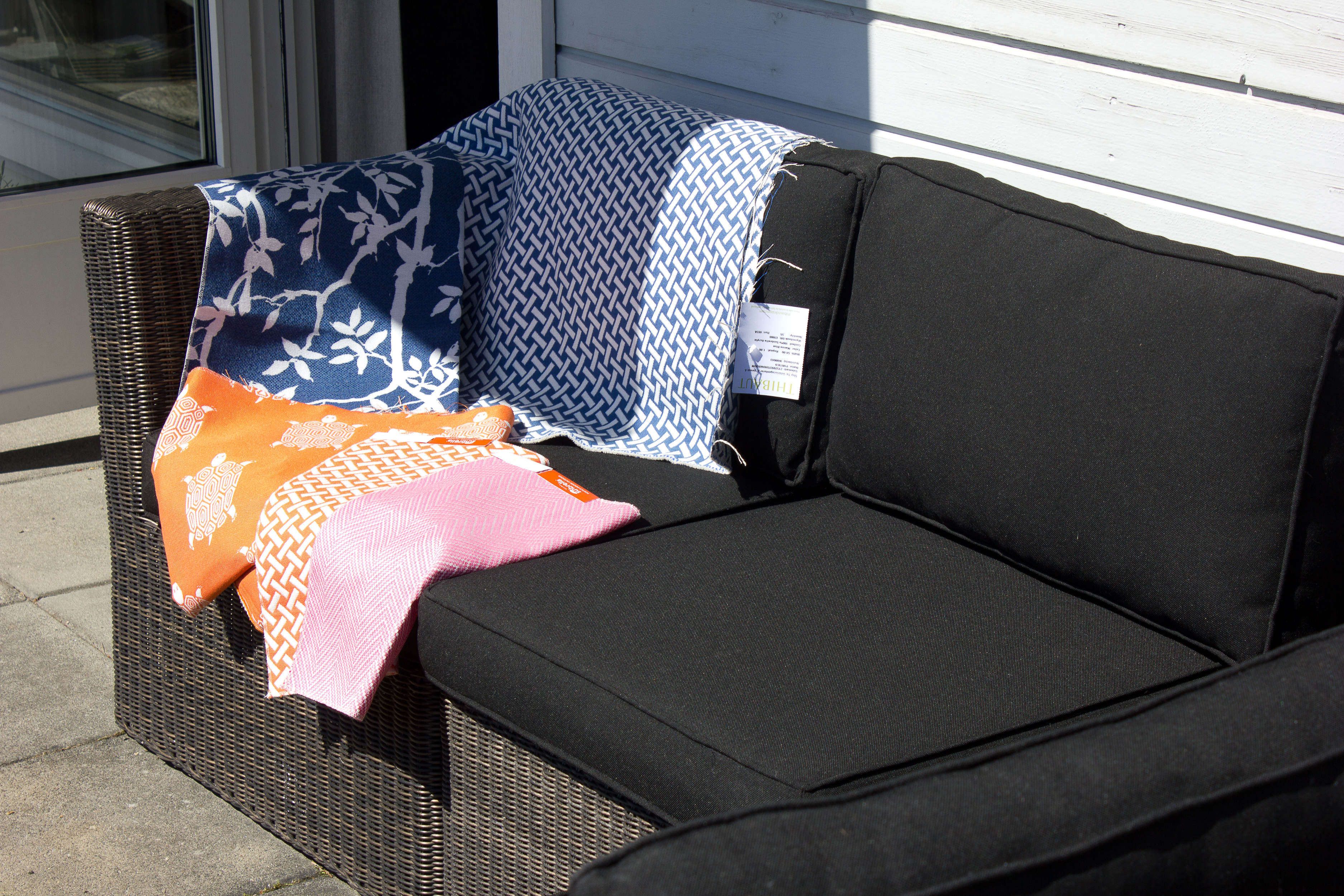 Ved å trekke om de sorte putene, eller legge til noen løse puter i sofaen, blir uttrykket med én gang mer sommerlig. Tekstilene finnes i mange farger og mønstre, så det er lett å finne noe som passer. Disse tekstilene er fra Thibaut.