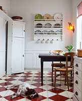 <b>GULV:</b> Det røde og hvite sjakkrutete gulvet er et skikkelig blikkfang. Det har fått litt støtte i den stripete gardinen og de mønstrede tallerkenene på veggen. Farge på gulv er Lust og Mjölk fra Beckers.