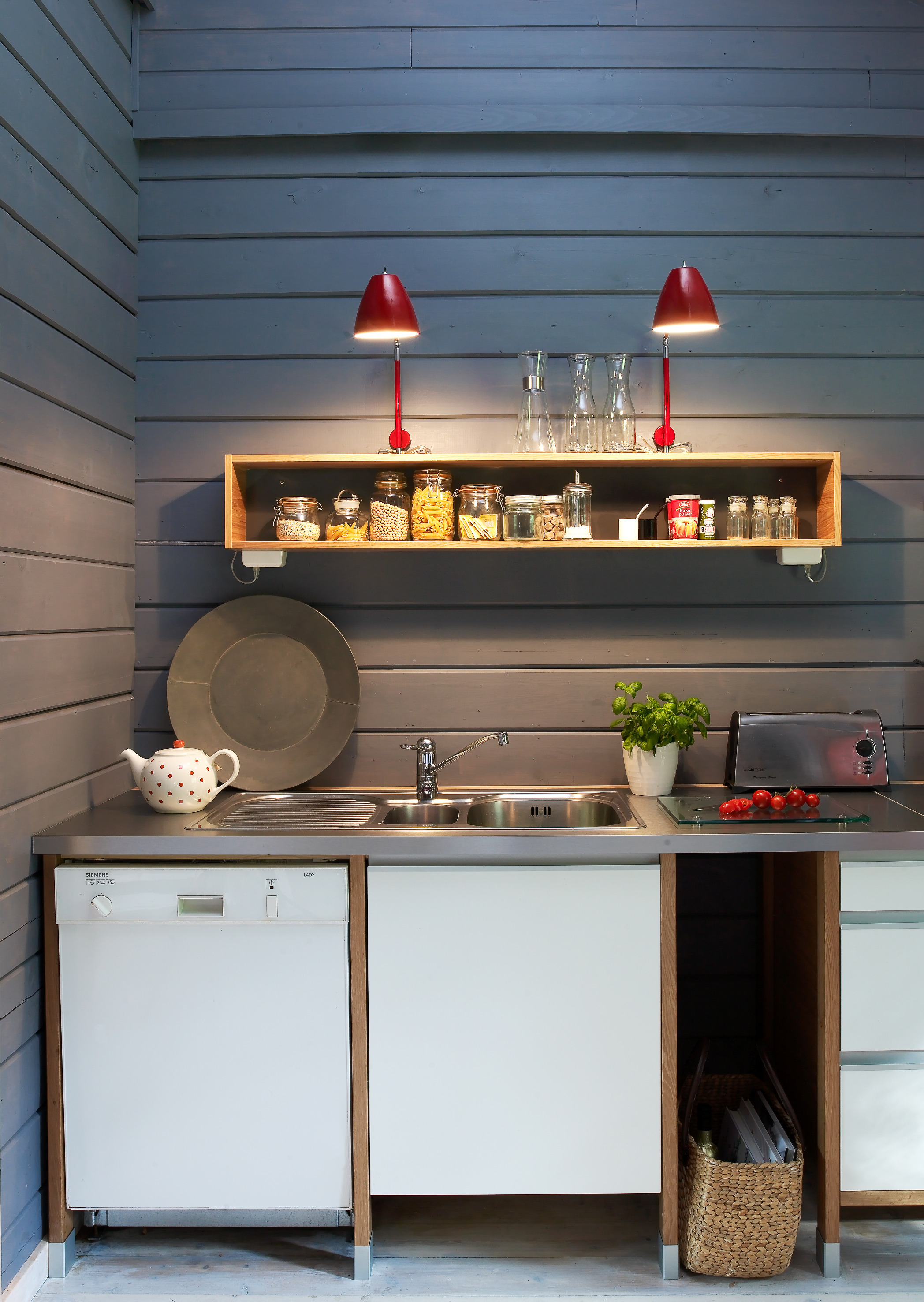 Mørk grå beis er lekkert mot de hvite skapene, og røde lamper utgjør et saftig fargeinnslag. 