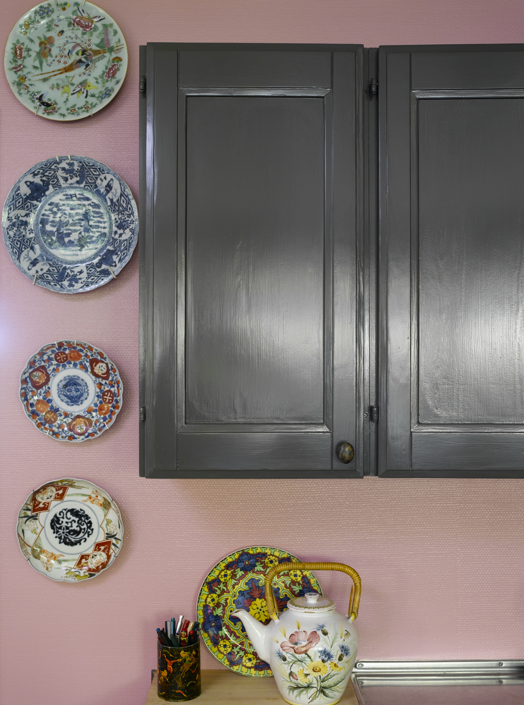 Den rosa veggen fremhever fargene i tallerkensamlingen, og er lekker mot de gråmalte skapene. Vegg i farge S 2030-R10B, skap i farge Royal Stone (Nordsjö). 