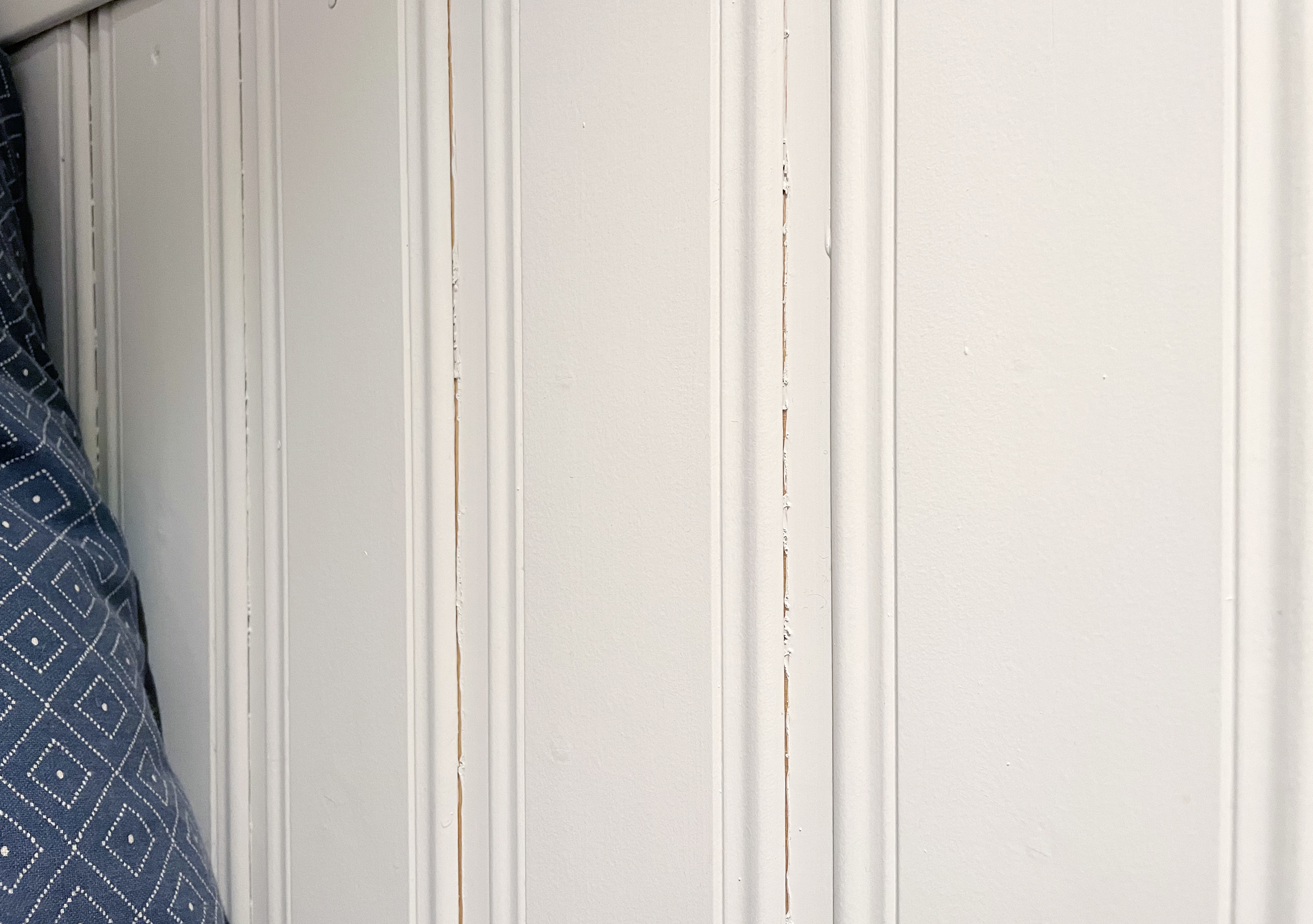 Krympesprekker synes i skjøtene på en malt panelvegg