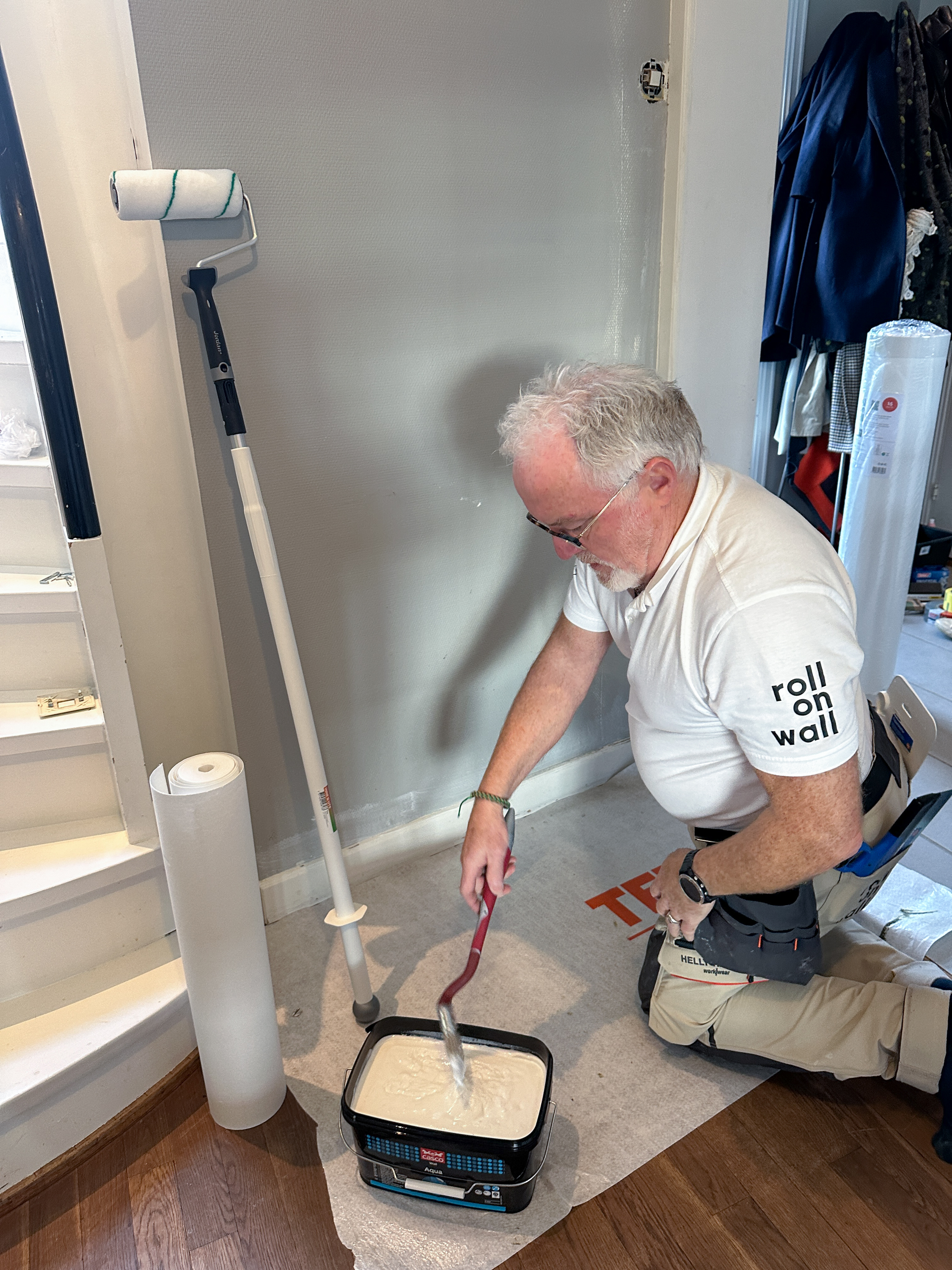 Mann sitter på huk og metter en pensel med våtromslim.