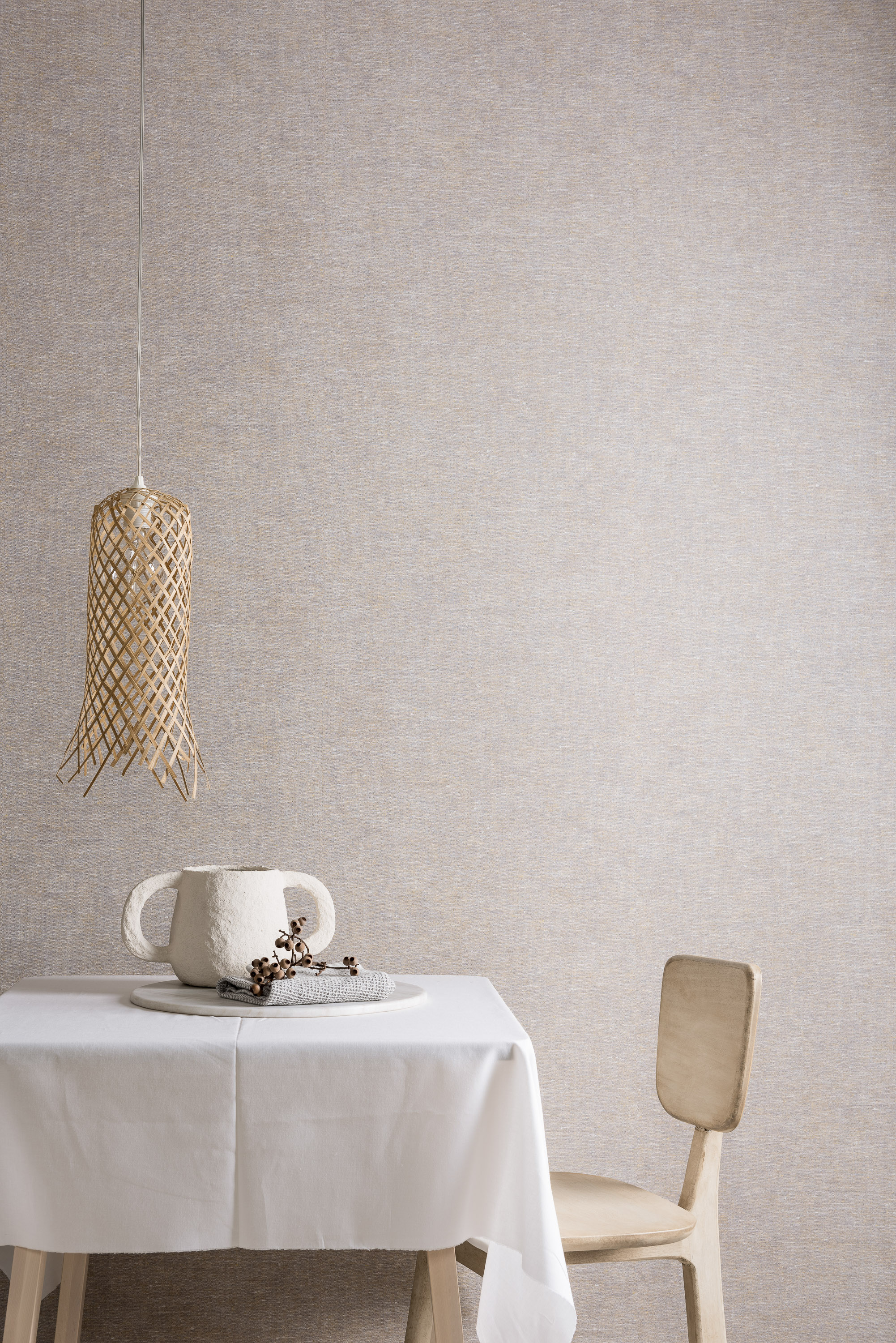 bord med duk og en stol foran beige vegg med tekstillignende tapet