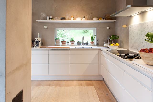 Den glatte kjøkkeninnredningen er en fin kontrast til gulv og vegger.
