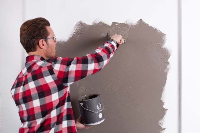 Påfør malingen på veggen med en rull eller en stor pensel.