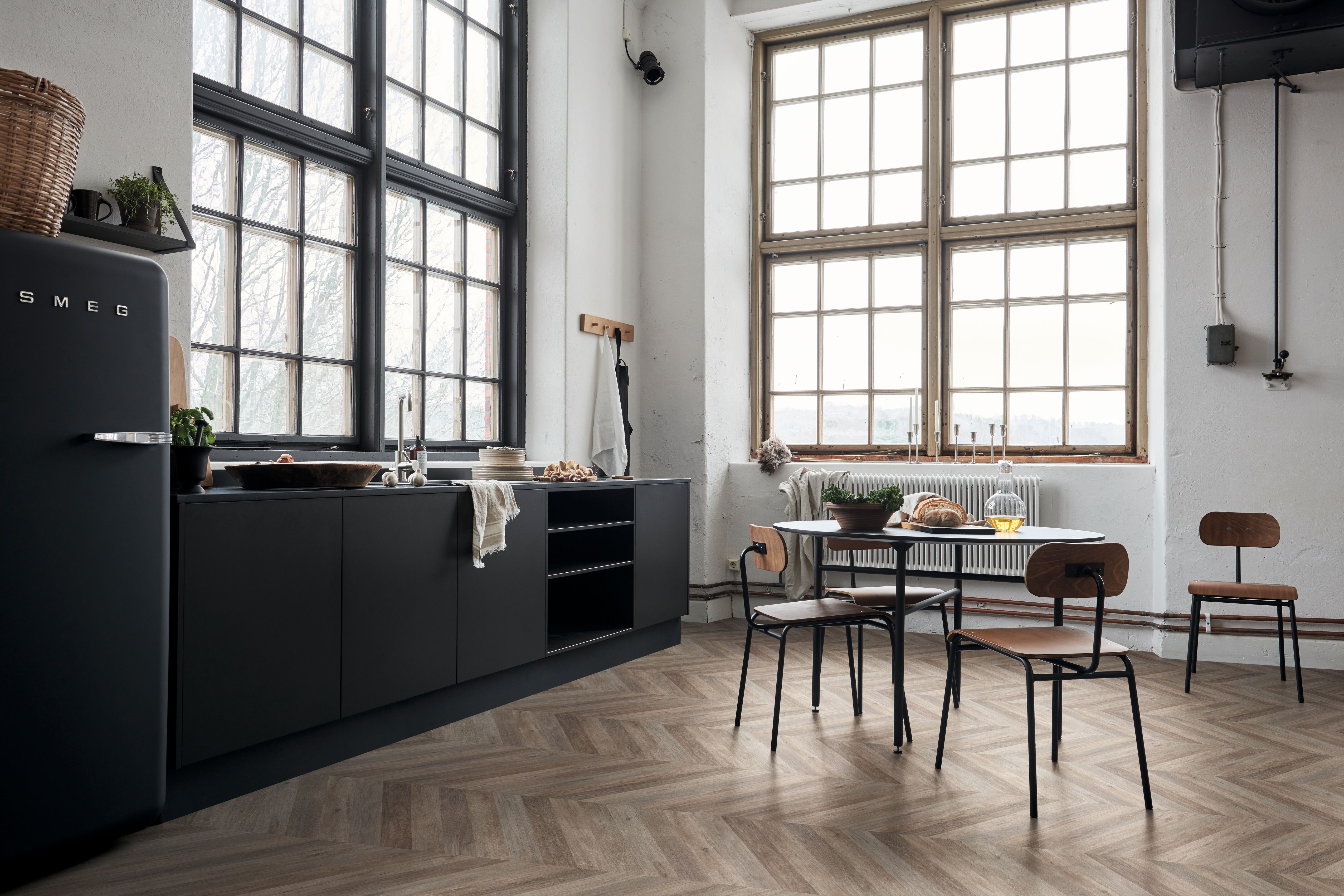 chevronmønstret gulv i mørke farger på gulvet i kjøkken med sorte skrog