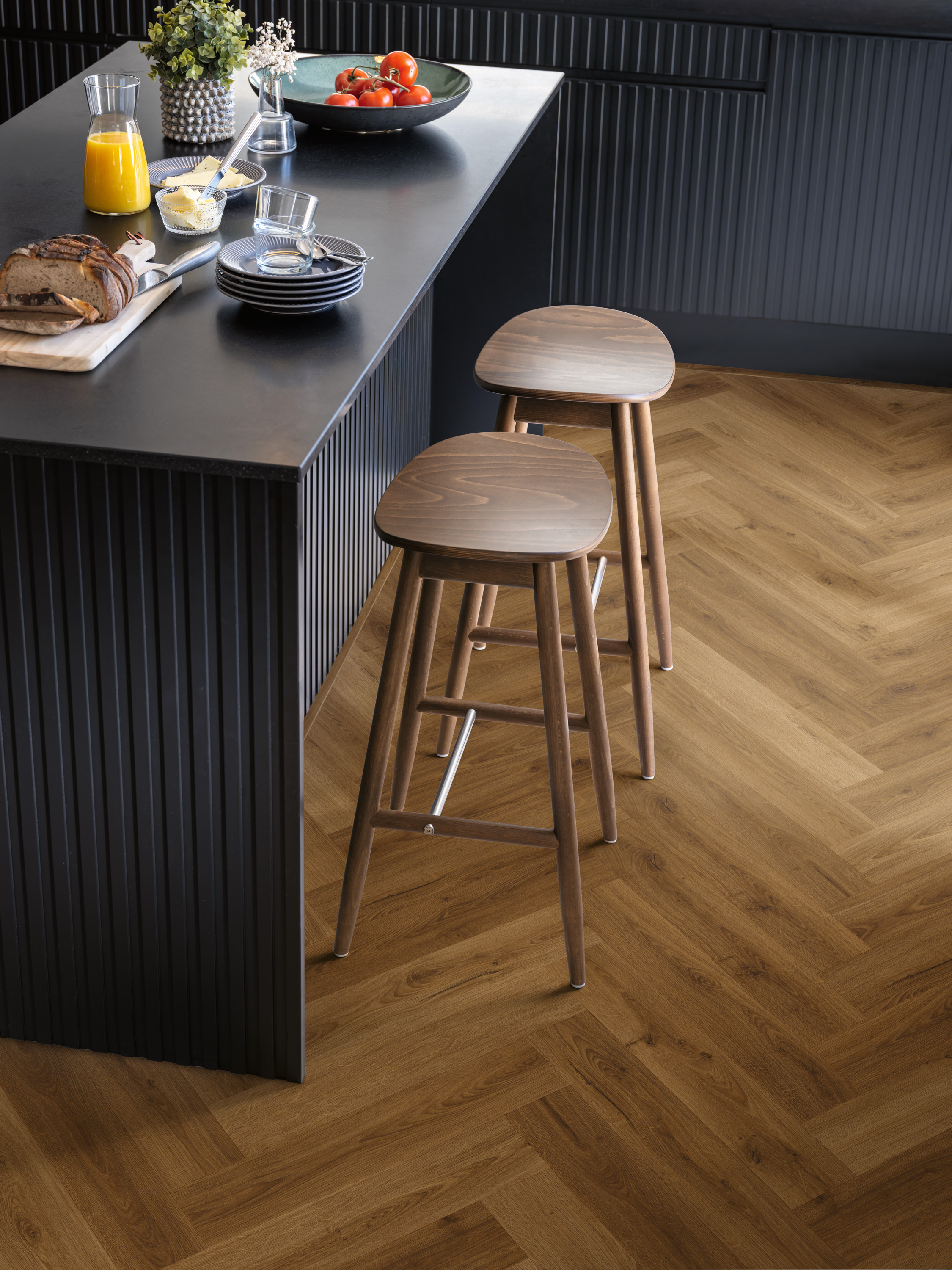 laminatgulv med fiskebensmønster på et kjøkken med sorte benkskap