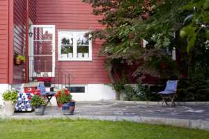 BLÅ DETALJER: Blåfargene er nydelige mot den røde husfargen. De gjentas i puter og krukker, som bidrar til å binde sammen uteplassen. 