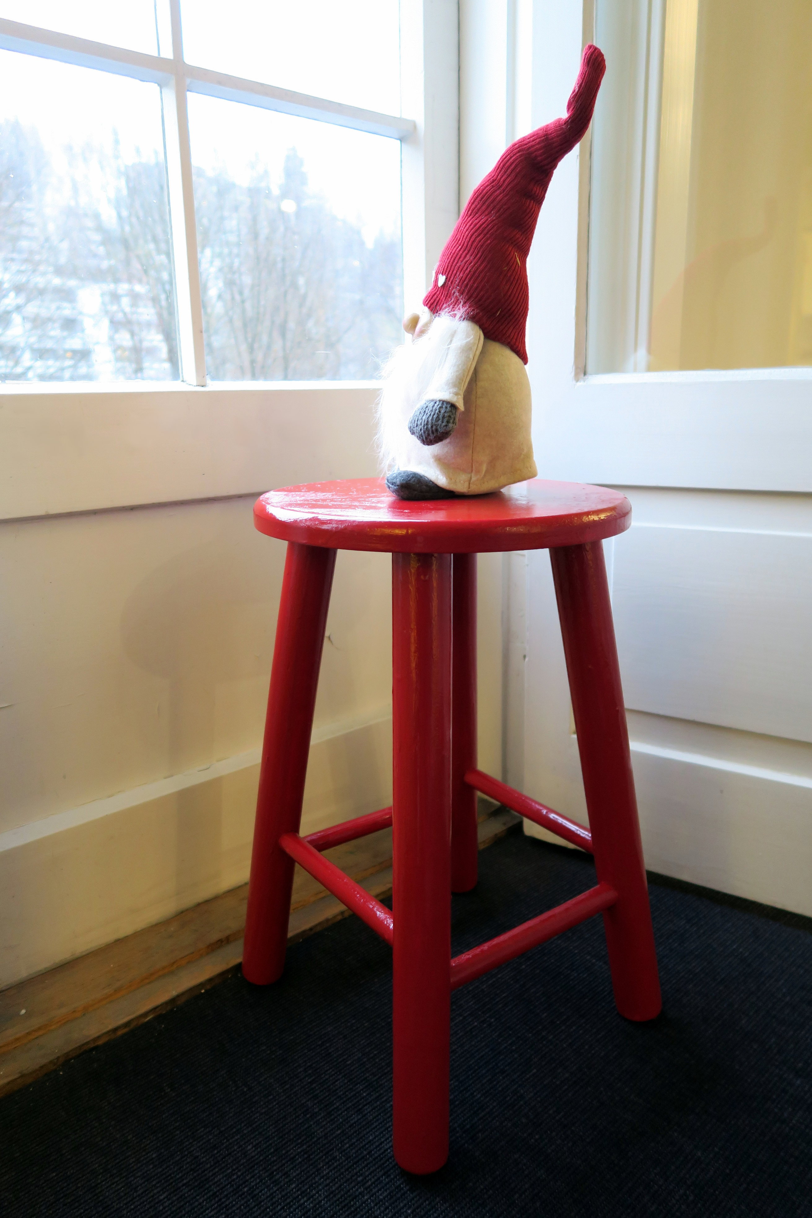 NISSEKRAKK: En rød krakk ved vinduet toppet med en nisse skaper julestemning. Krakken er malt med gulvmaling i fargekoden RAL3003.