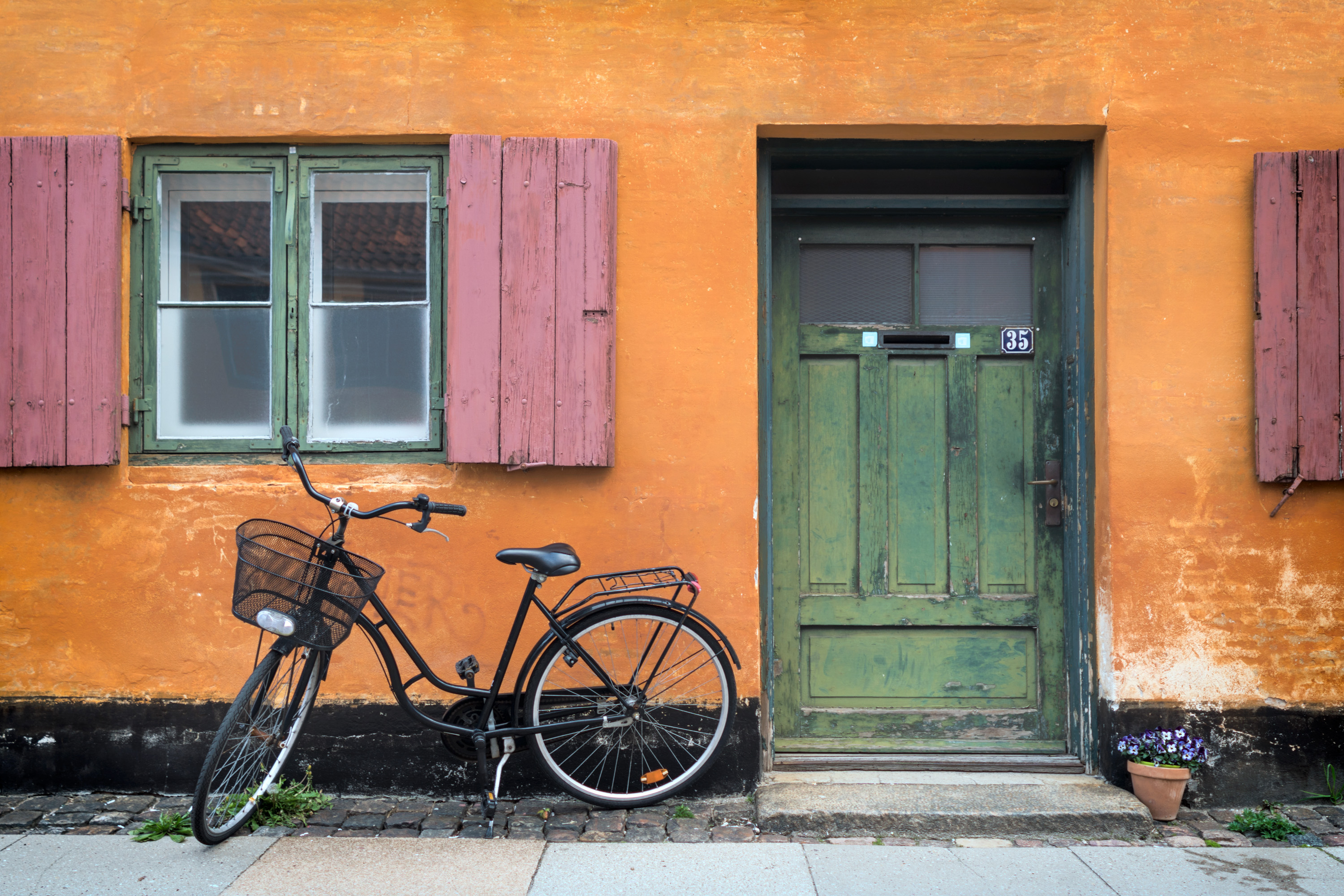 oransje hus med grønn dør og sykkel foran
