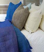 Et vattert sengeteppe i bomull er mykt og fristende å slenge seg ned på! Putene er plissert - noe som gir en spennende effekt. Pleddet er av mohair.