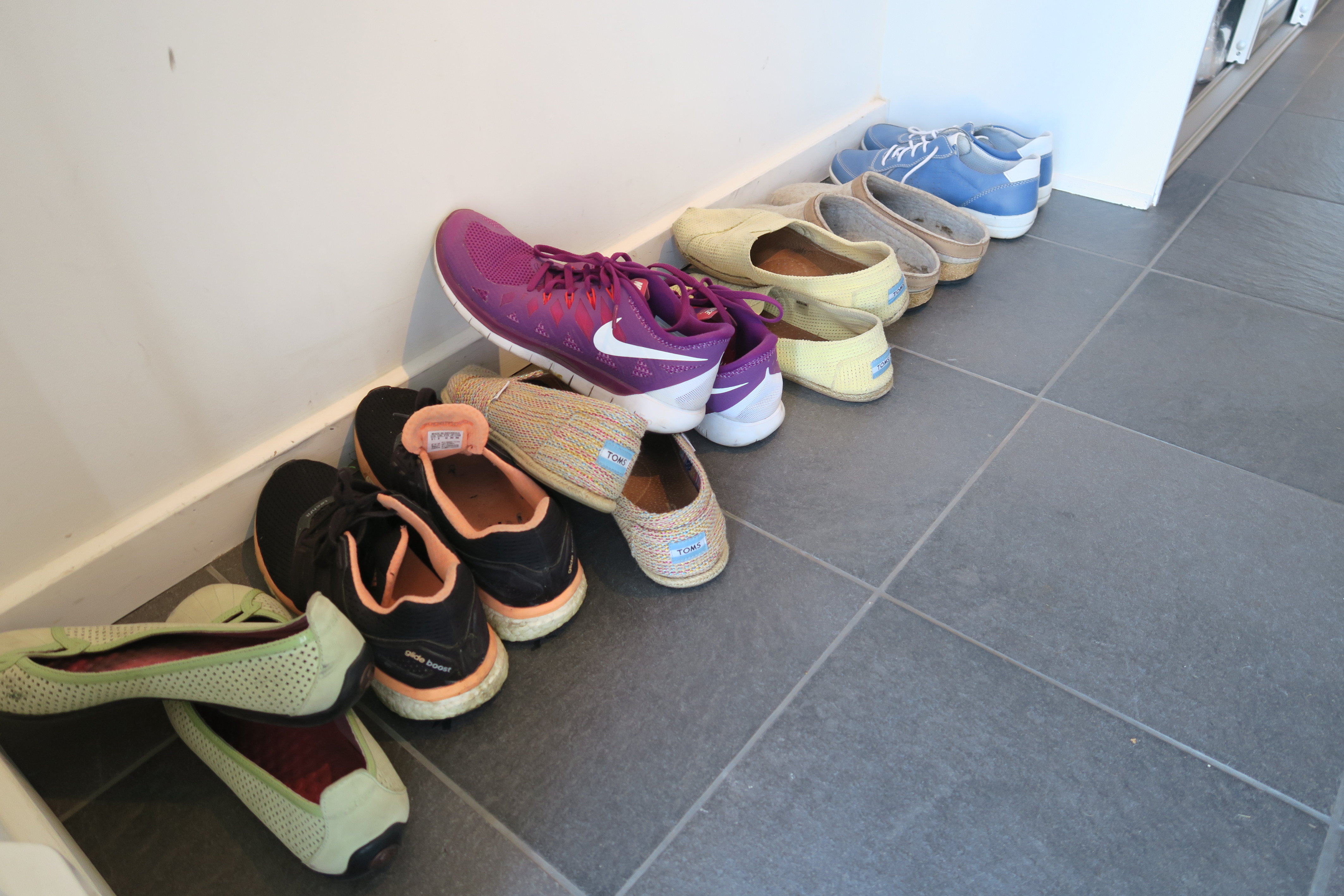 Noen sko ligger og slenger på gulvet. Andre har sitt eget stativ. En gummi- eller teppeflis på veggen sørger for at skoene ikke skitner til.