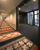 Teppebelagte korridorer hvor interiørarkitekt har valgt en modifisert variant av ege-mønsteret Village Print. I områdene foran heisene er det mest praktisk med et ensfarget grått teppe.