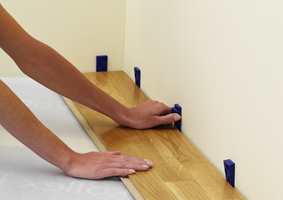 Husk at gulvbordene helst skal legges i rommets lengderetning. Begynn i et venstre hjørne med notsiden inn mot veggen, og jobb deg mot høyre. Trykk ned kiler mellom gulvet og veggen for å lage en bevegelsesfuge på ca. 8 - 10 mm.
