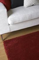 Et rødt, flott teppe i salonggruppen er knyttet i ull og lin, og binder møbelgruppen sammen. 