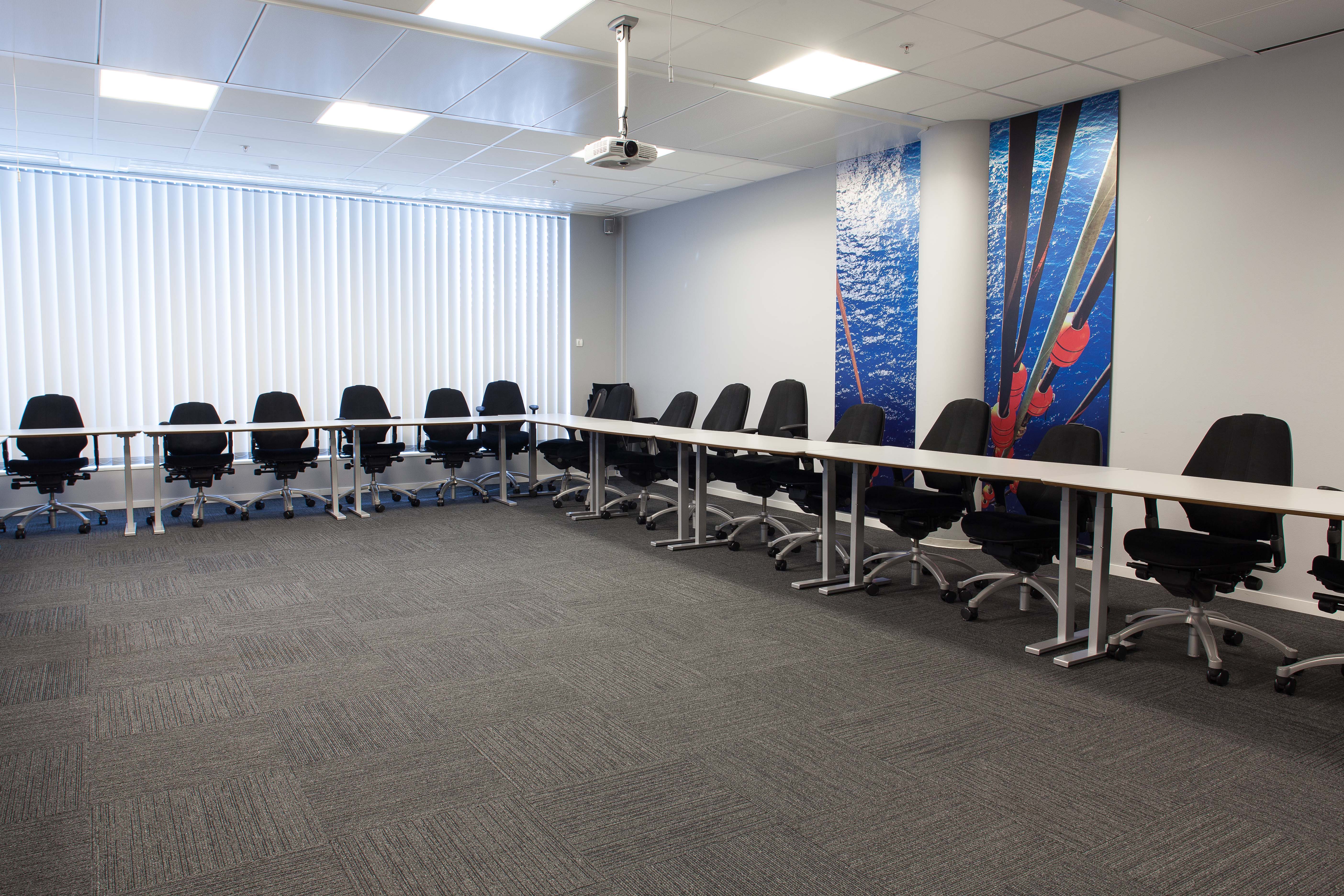 Gråtonene i møterommet brytes opp av fargesterk veggdekor.