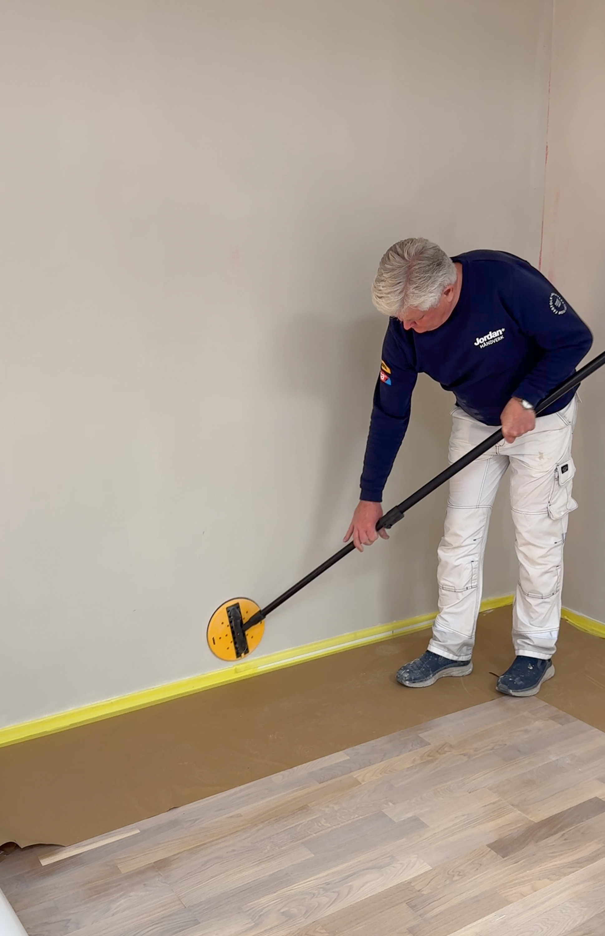 Mann sliper gipsvegg med slipeverktøy,