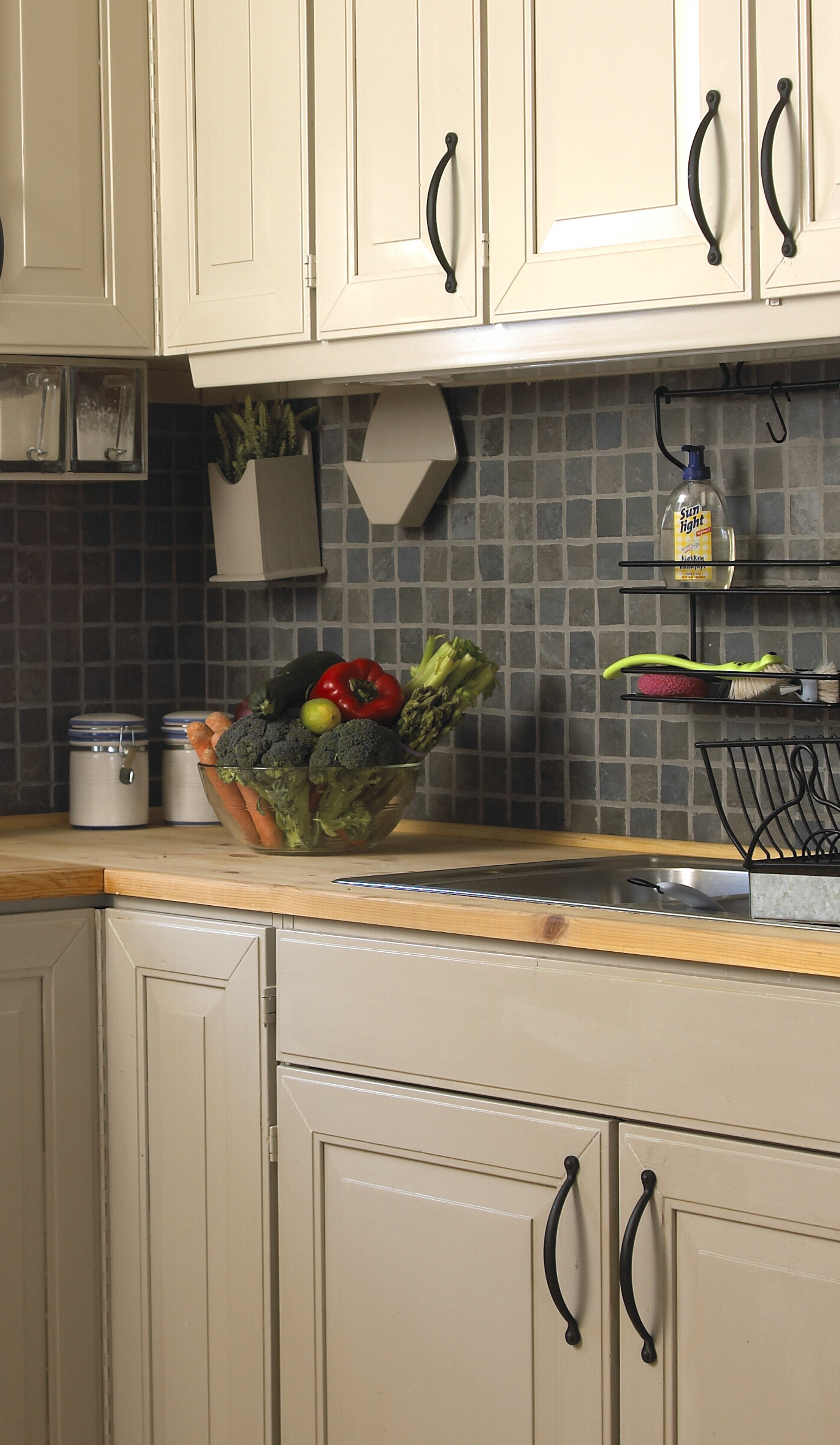 Overskapene er malt i en lys gråfarge, mens underskap og sokler har fått en mørkere nyanse. Rustikke kjøkkenfliser med steinpreg understreker den røffe stilen på fjellhytta, og tar opp de varme gråfargene på vegger og innredning. 