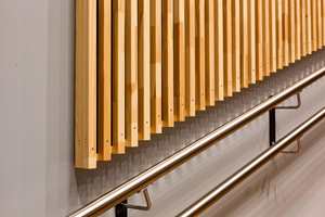 <b>TRESPILER:</b> Trespilene som pryder veggen er furu som har vokst opp ved Mjøsa. Ved trappen i auditoriet er sideveggen malt i en gråblå tone. Bak trespilene er det montert akustikkduk, som bidrar til godt lydmiljø i rommet.