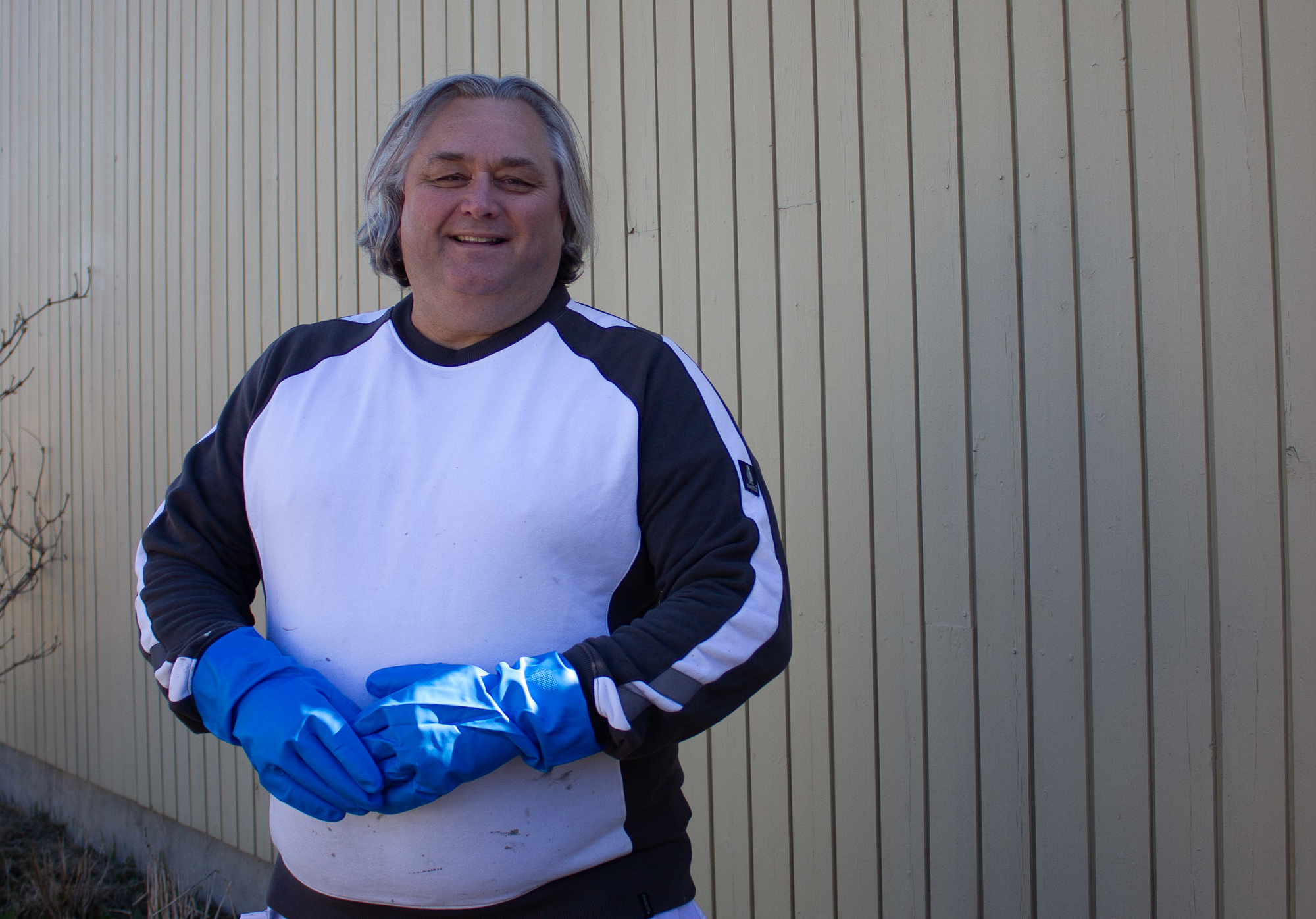 mann i malerklær mot gulbrun vegg