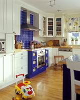 Kjøkkenet med eggeskallhvit innredning kler blå detaljer.