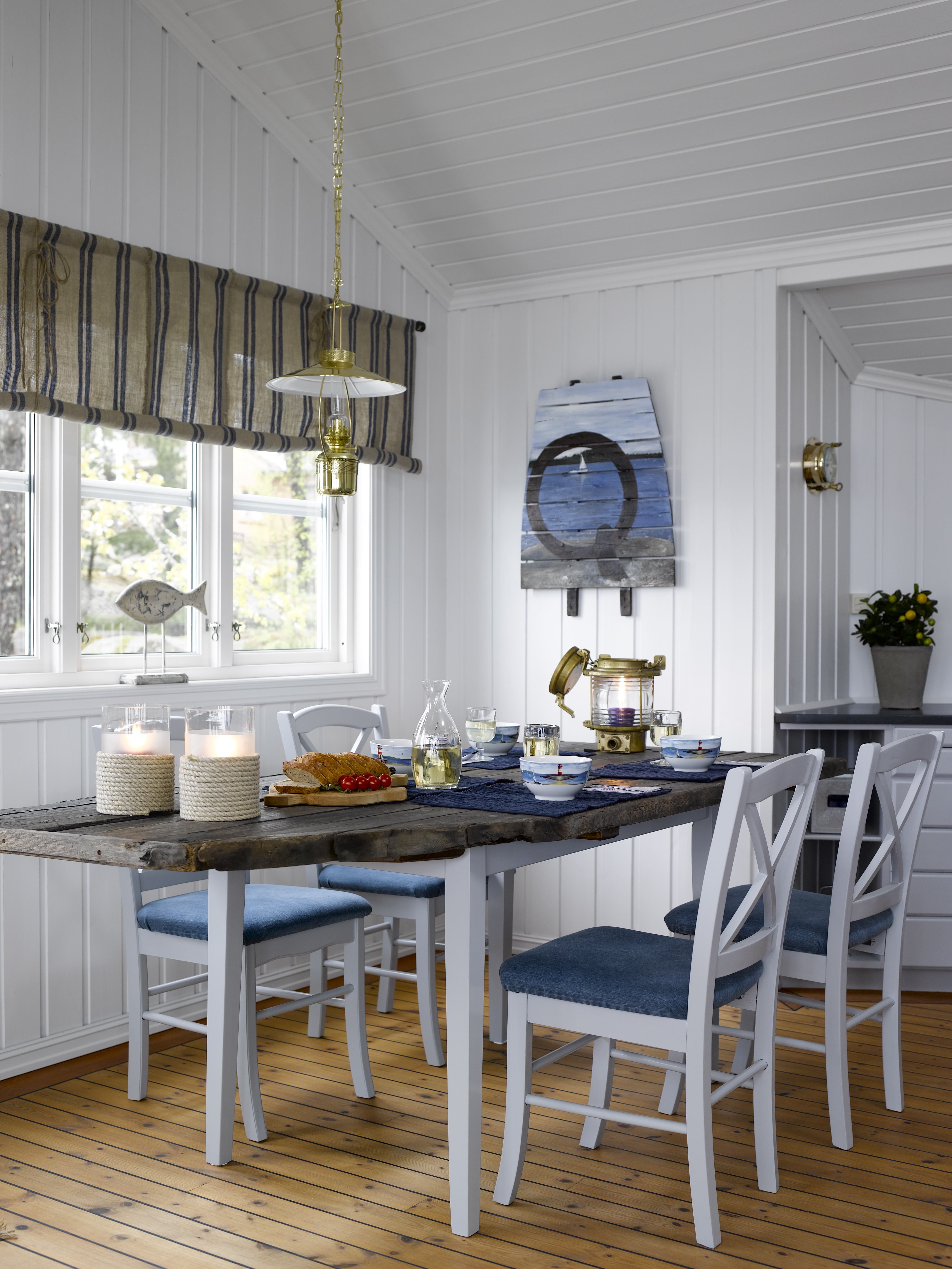 Veggene er lyse, understellet på spisebordet er malt i en gråfarge, stolene likeså. Den nye bordplaten er laget av drivved. Gardinen tilfører rommet tekstur og en lett tyngde.