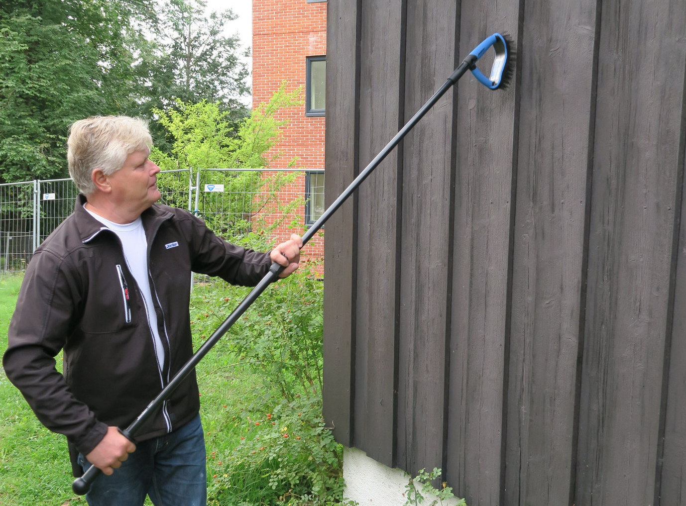Maling og løse rester må skrapes av husveggen før den kan males.