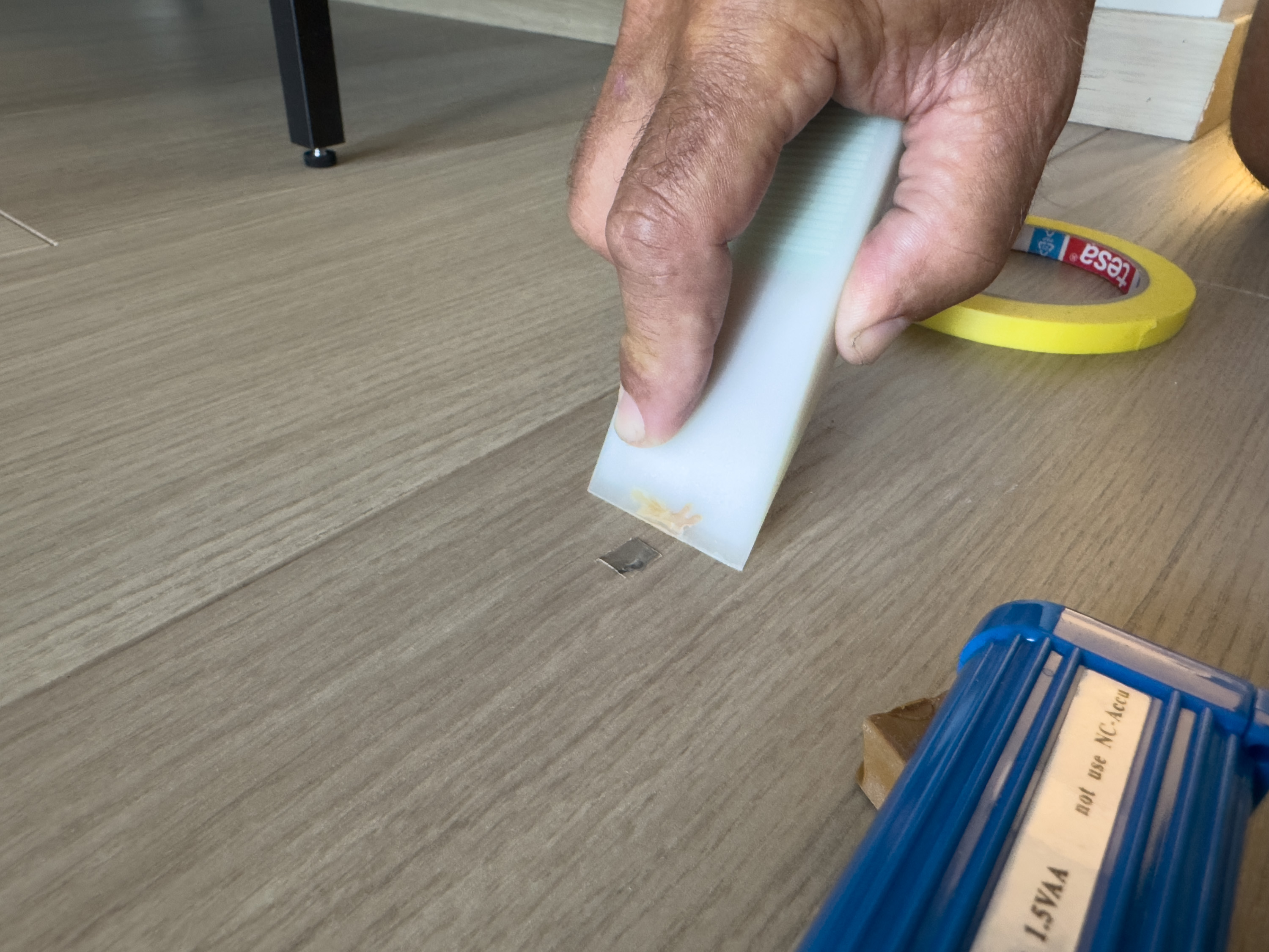 skrape skraper bort overflødig voks fra sår i laminatgulvet.