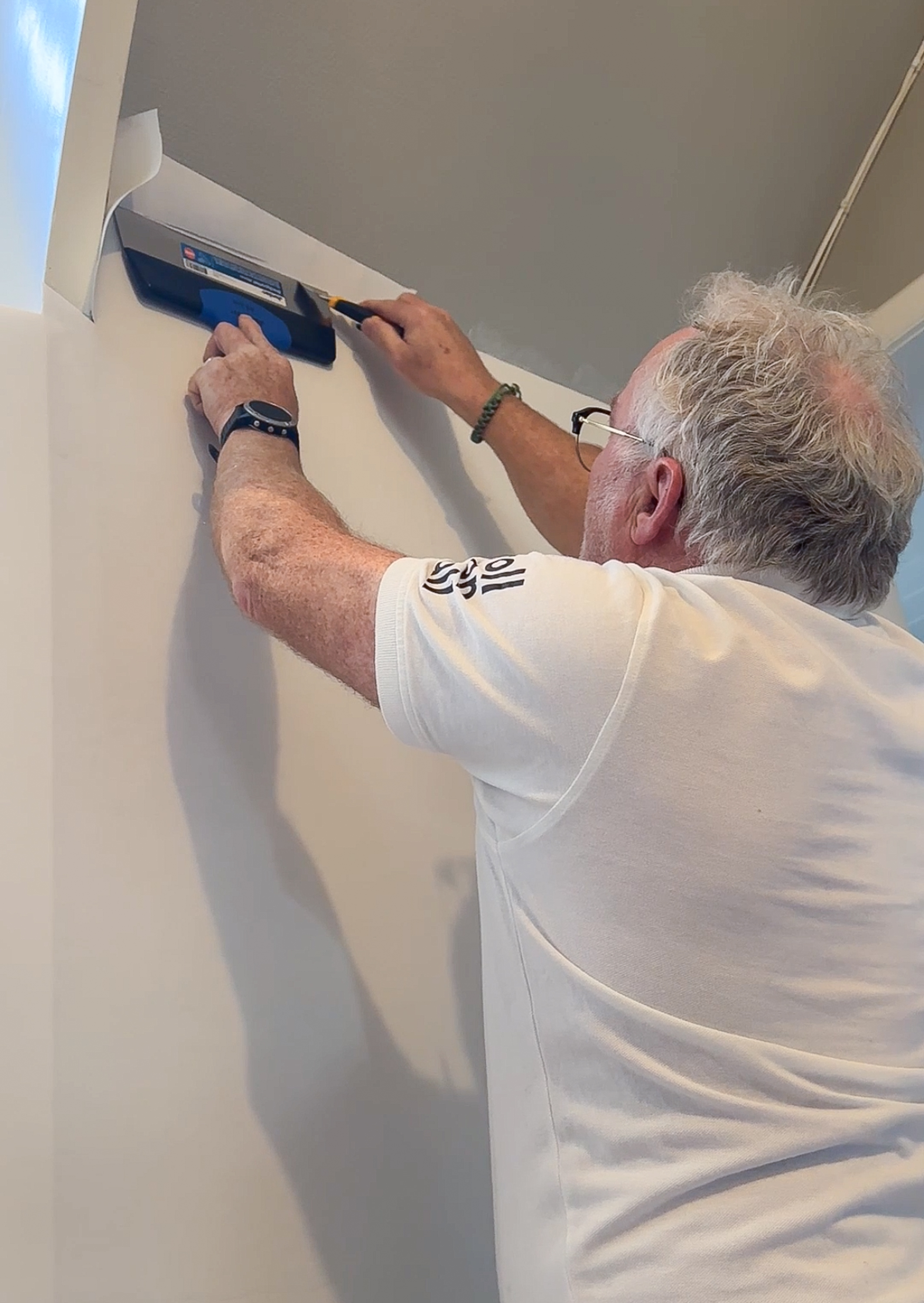 Mann skjærer til veggfornyer på et skråtak.