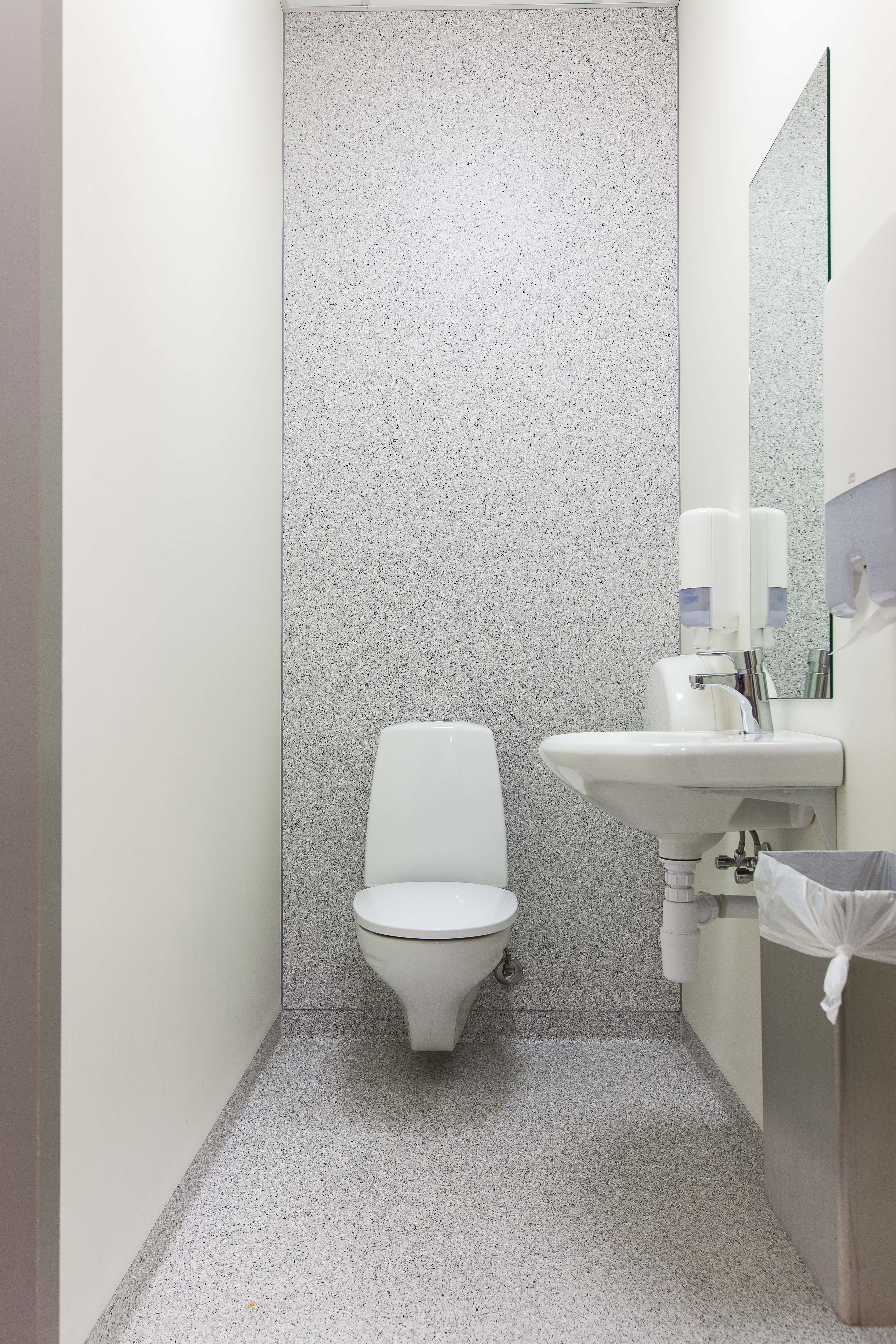 På toalettene er gulvbelegget strukket videre opp på bakveggen, slik at den fremstår nærmest som en fondvegg.