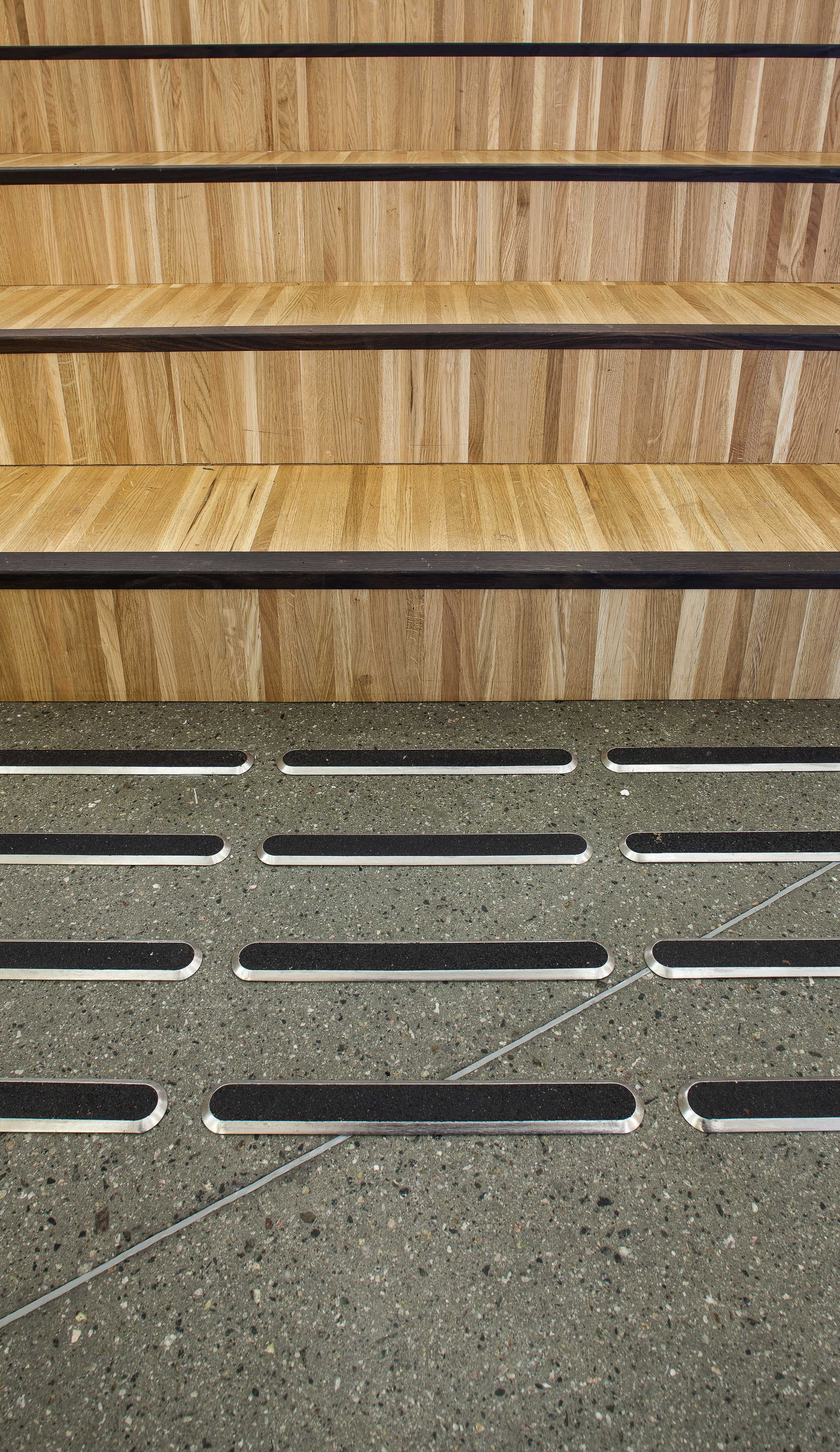 Trappetrinnene i auditoriet er kledd med små lameller i tre, gjerne kalt industriparkett. 