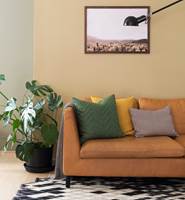DYBDE: I et rom malt i varme farger gir små innslag av sort rommet dybde og strammer opp helheten. Veggene bak sofaen er malt med Butinox Interiør Stue & Sov Matt farge 5939 Dijon.