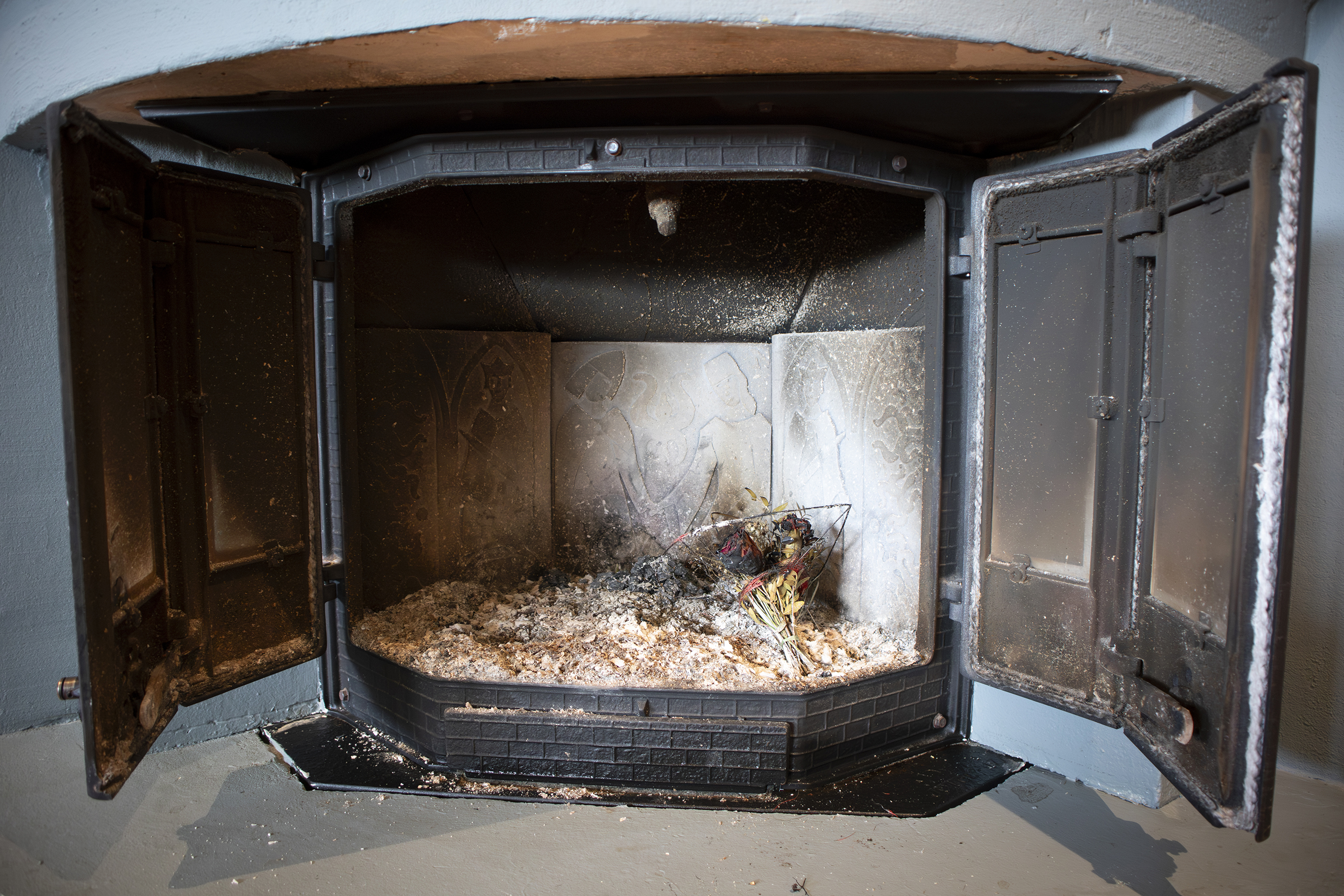 En peis som står åpen med aske i bunnen.