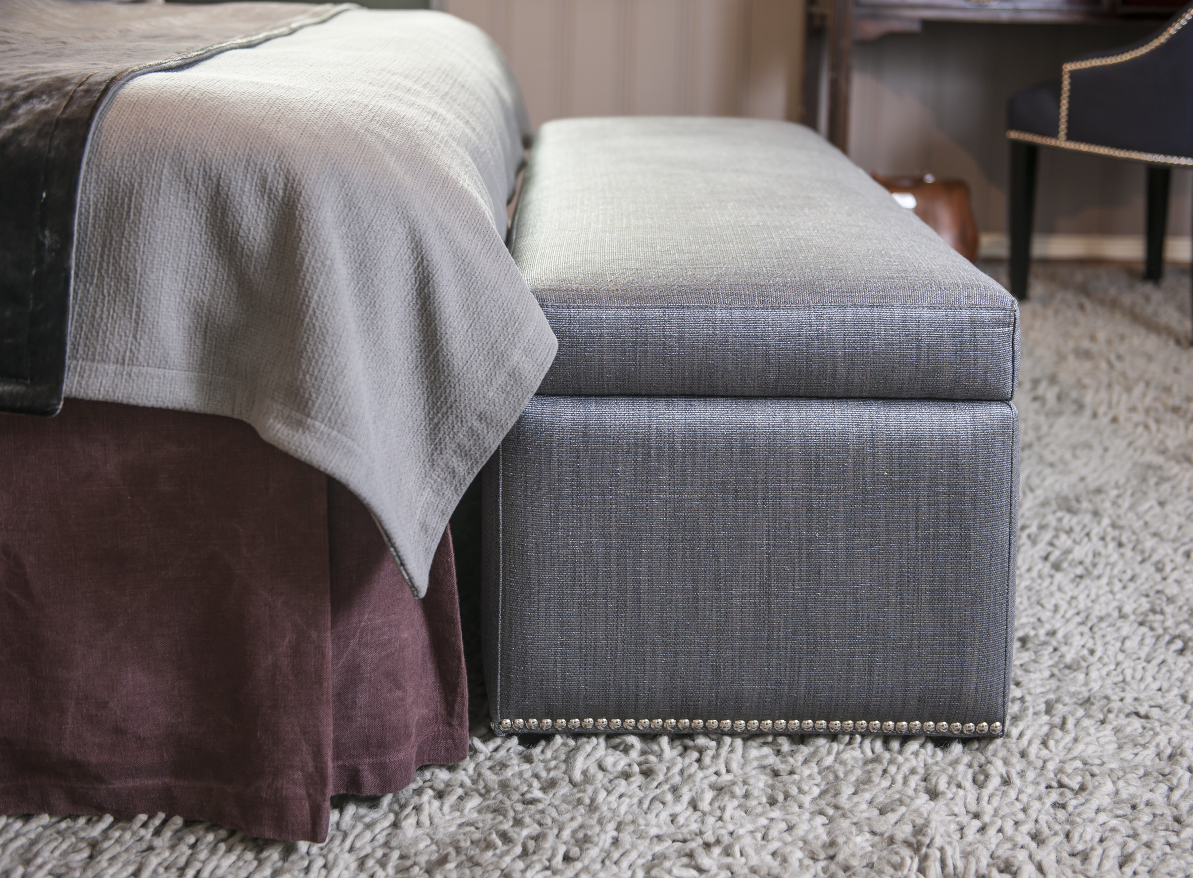 FOTSIDT SKJØRT: Sengeskjørtet i stenvasket lin faller lekkert mot gulvteppet. To sengetepper, det ene i velur, og en puff i et blankere tekstil, er en spennende miks av teksturer. 