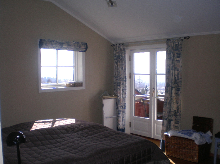 Franske dører leder ut til terrassen – et lekkert tilskudd til interiøret. Vinduet på veggen tilfører fint sidelys. For øvrig er ganske upersonlig rom. 