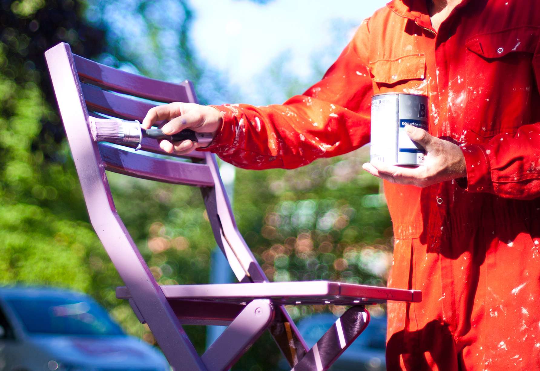 mann i oransje kjeledress maler utestol lilla 