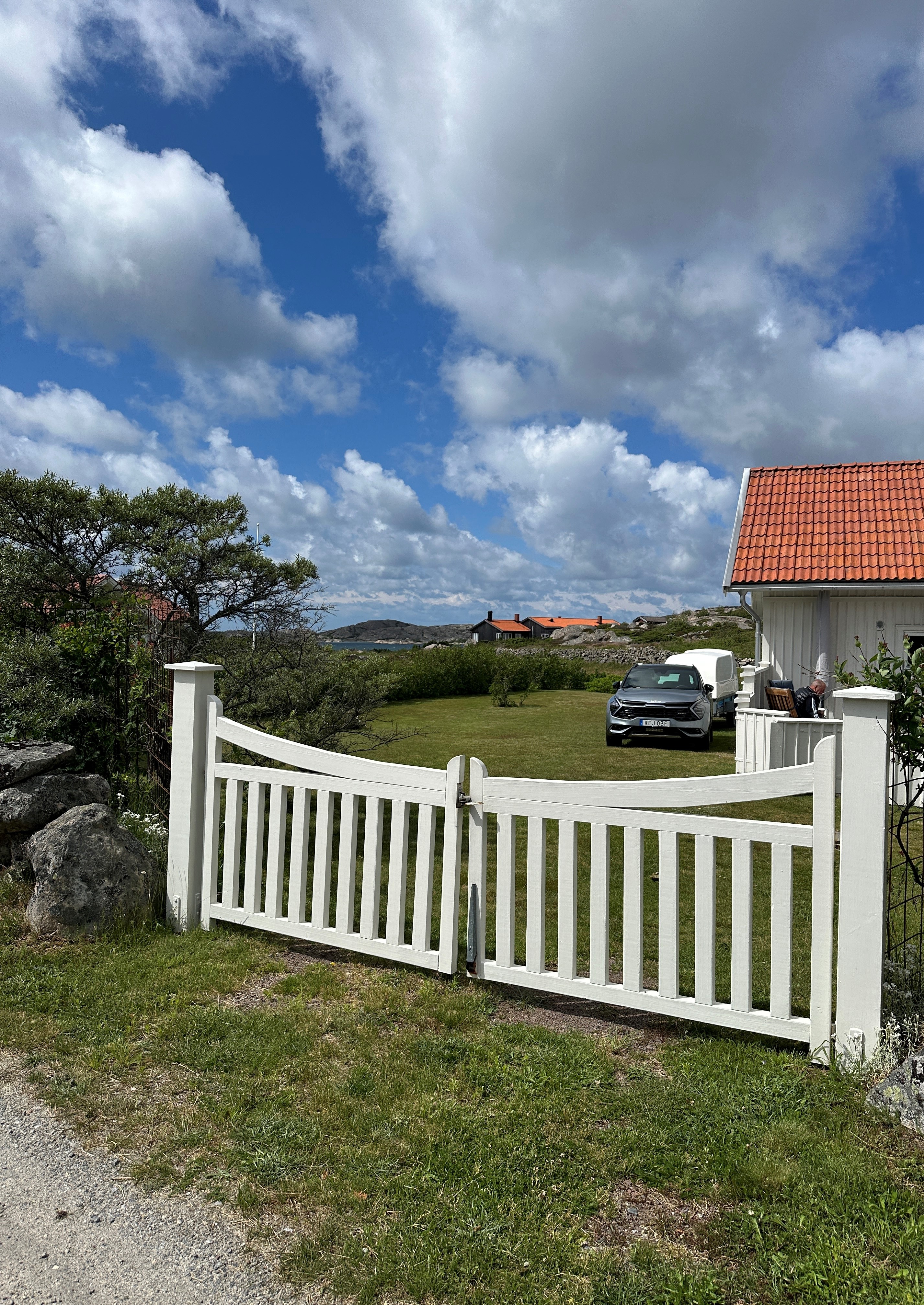 natur hvitt hus rødt tak hvit port
