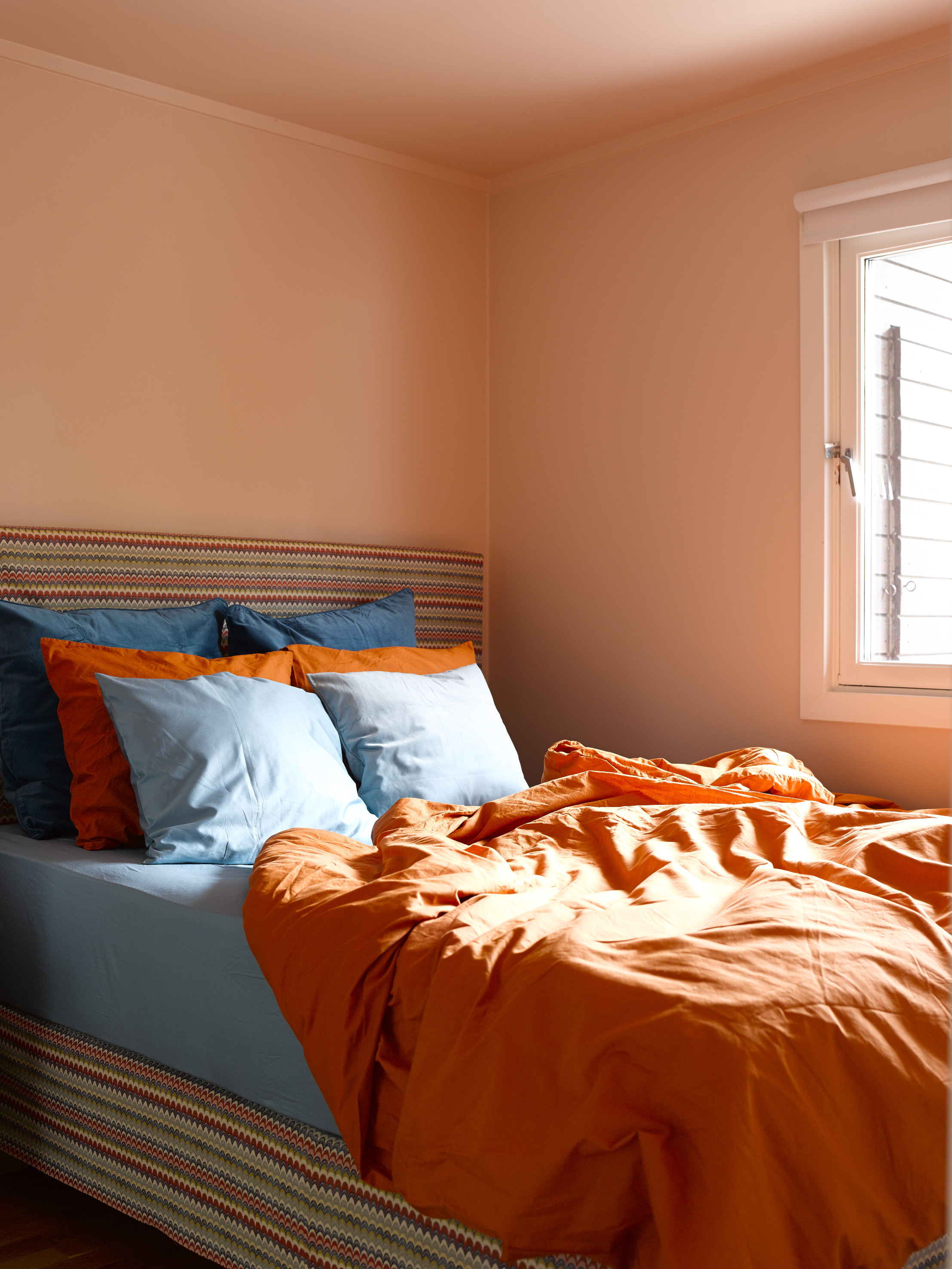 På soverommet er den oransje tråden fra kjøkkenet tatt opp, i en dempet, pudderoransje variant  (S 1010-Y70R). Tak, vegger og listverk er malt i én og samme farge, noe som forsterker fargeeffekten. 