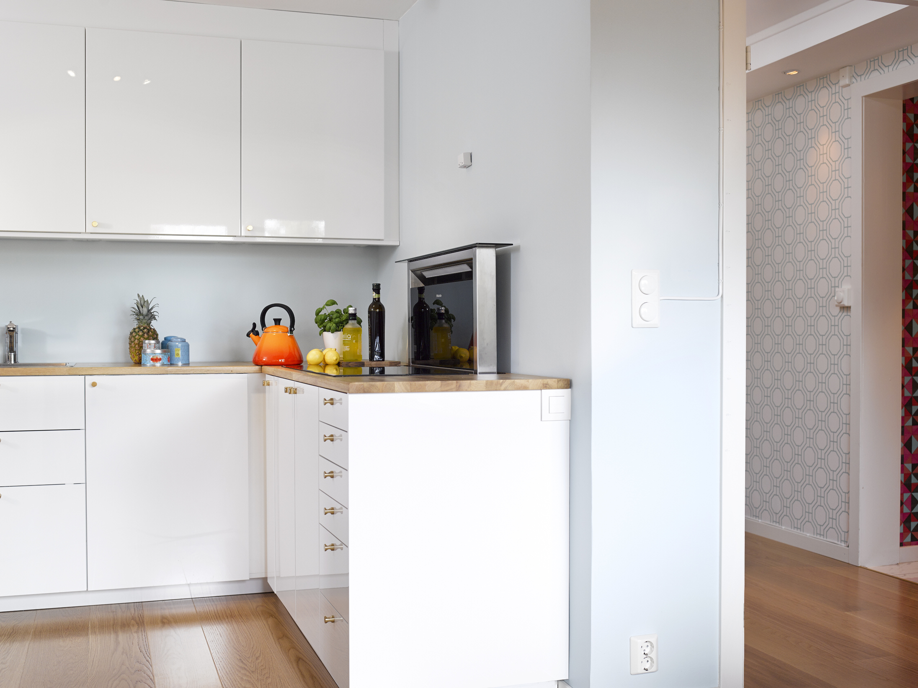 Avstemte kombinasjoner; det er ingen sak med åpen løsning når fargene spiller så godt på lag – kjøkkenet mot stueveggen. Og til høyre aner vi tapetet i gangen, som også har den blågrønne fargen i seg.