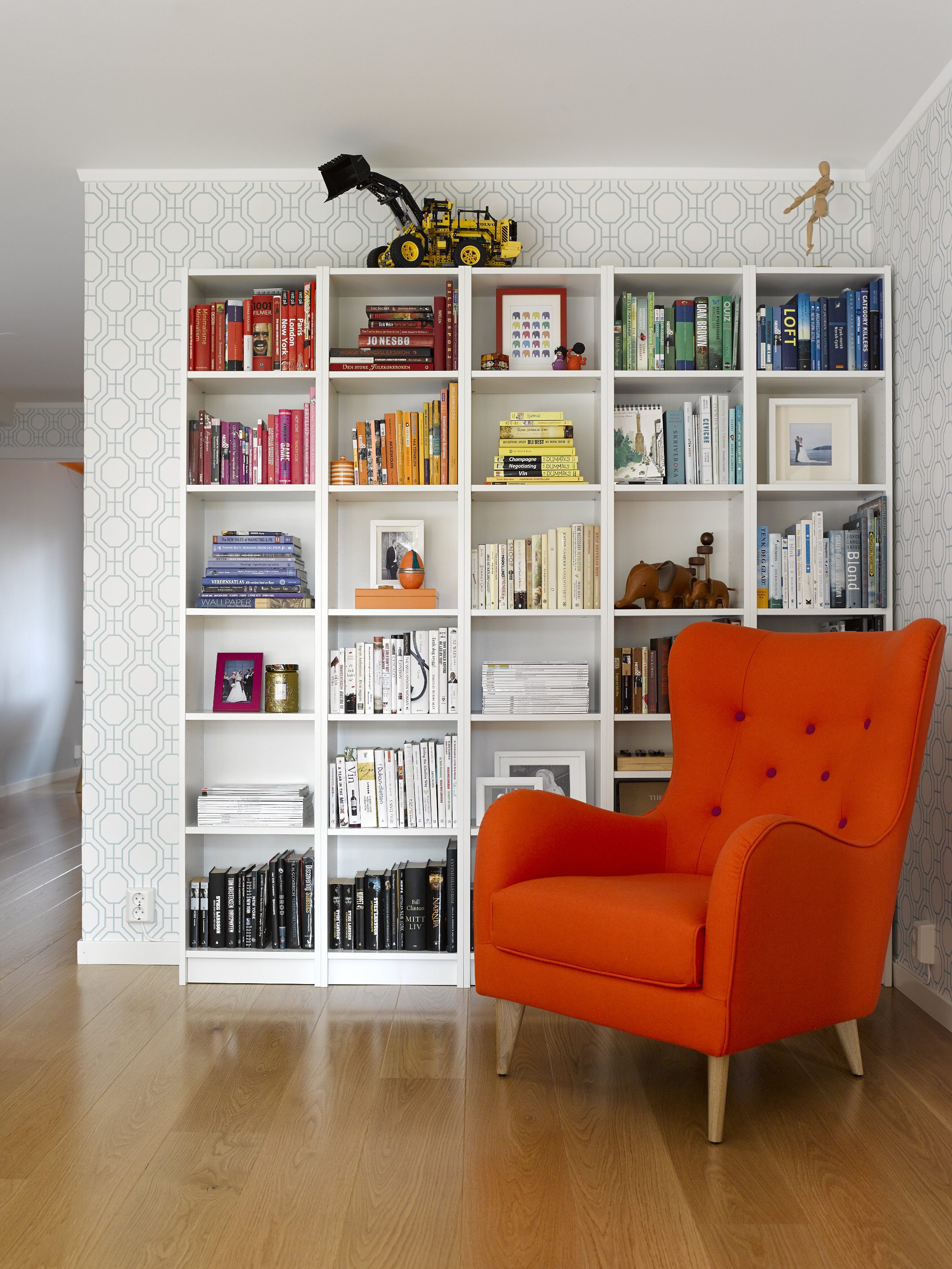 Tapetet Norsk Trellis, i fargen blågrønn – danner en delikat og nedtonet ramme for bokhylle og stol. 