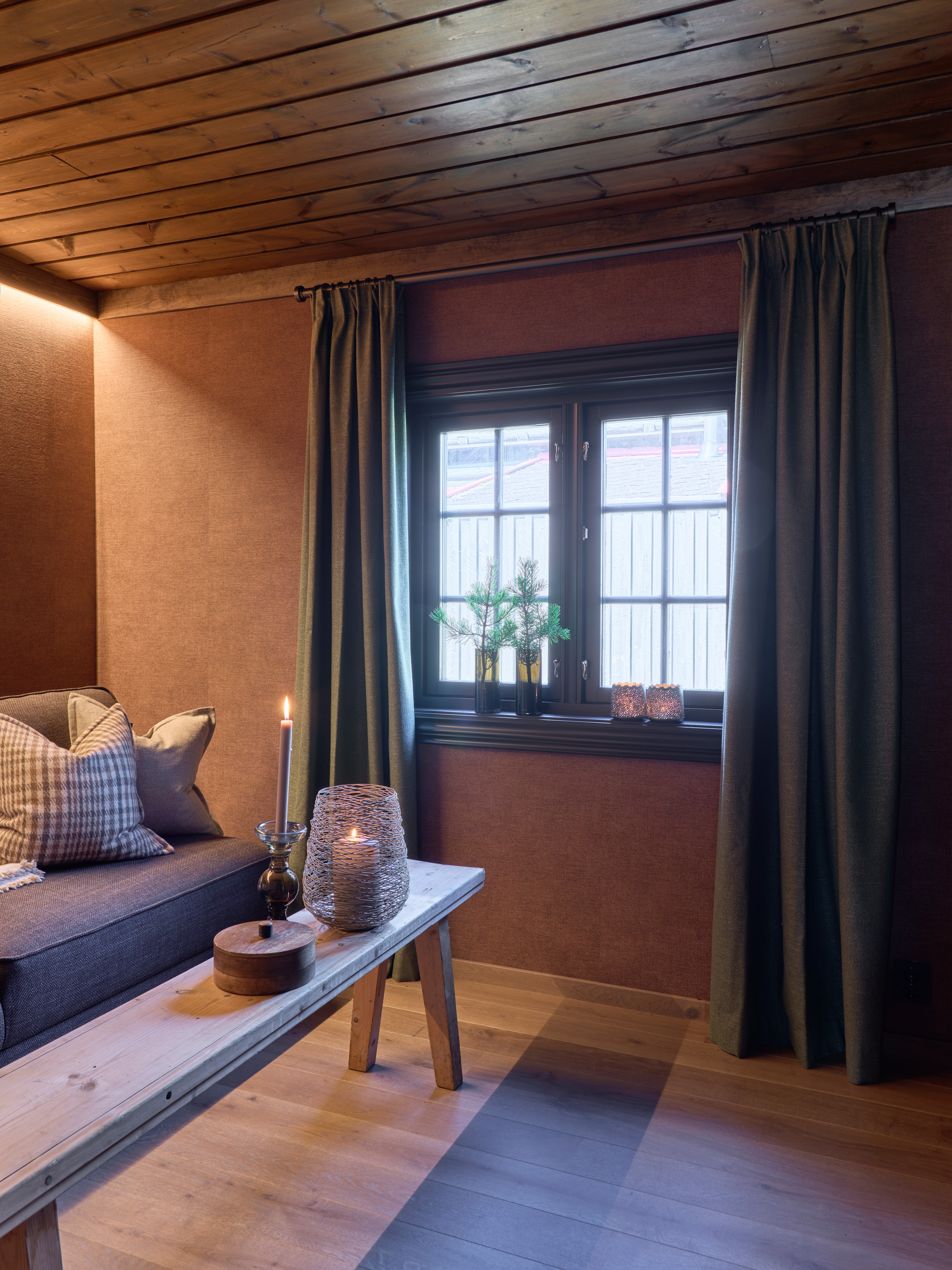 Rom med tregulv og vindu på veggen. mørk vindusomramming og gardiner. tapet på veggen i en terrakotta-farge