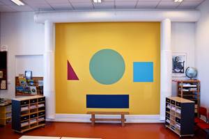 I klasserommet er krittavlen et velkjent arbeidsverktøy. 1. klasse ved Langestrand skole har fått en helt unik variant – med gul tavlemaling og uliktfargede geometriske figurer over en hel vegg.