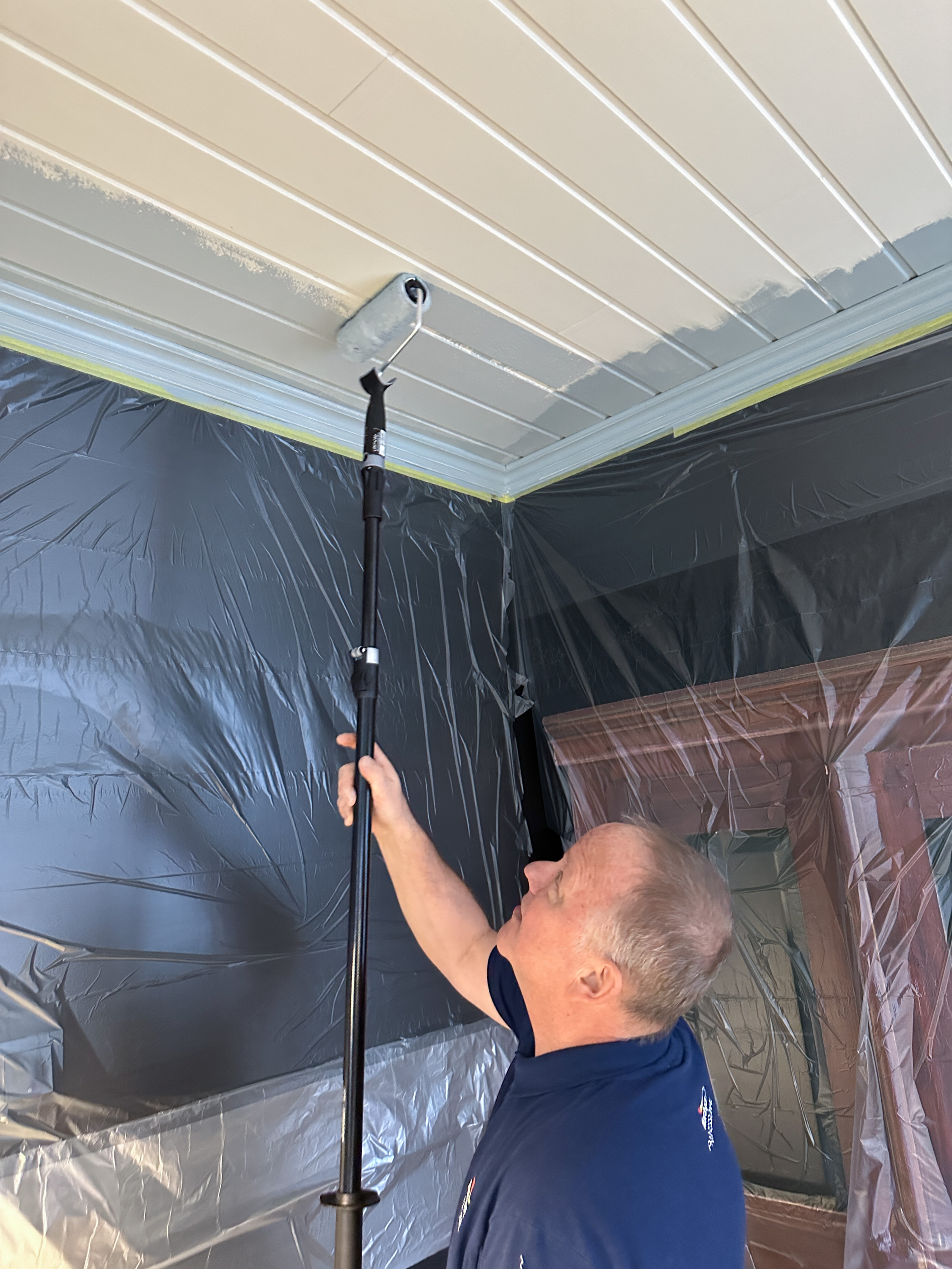 Per Myhre maler paneltak med rull.