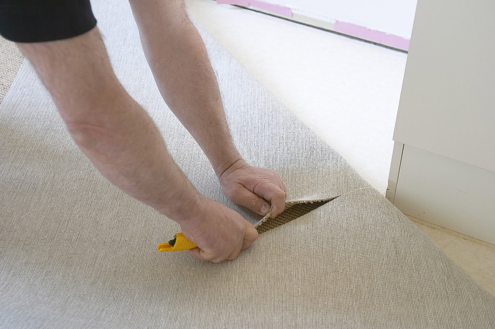 skjærer snitt i teppet ved ytterhjørne